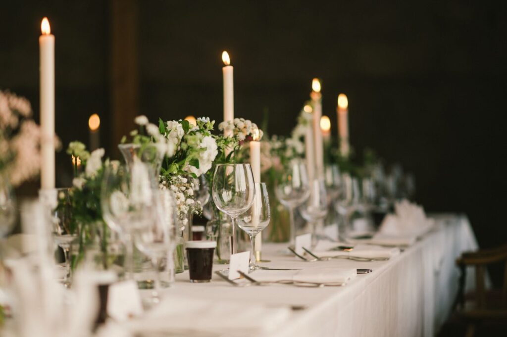 Stilvoll gedeckter Hochzeitstisch mit Kerzen, weißen Blumen und Glasglaesern – stimmungsvolle Kulisse für Eheringe Platin