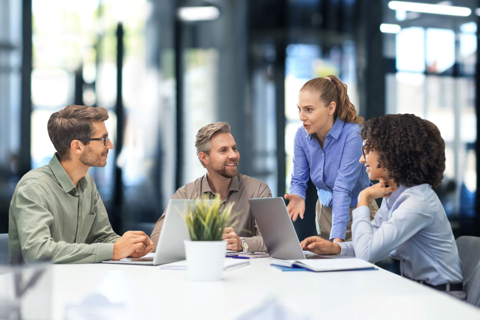 Team im Buero mit Laptops im Gespraech, Symbol fuer Zusammenarbeit, Vertrauen und Kommunikation zwischen Unternehmen und Lohnbuero